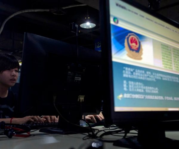 Computer users sit near a monitor display with a message from the Chinese police on the proper use of the Internet at an Internet cafe in Beijing, China. (Photo: AFP/VOA)